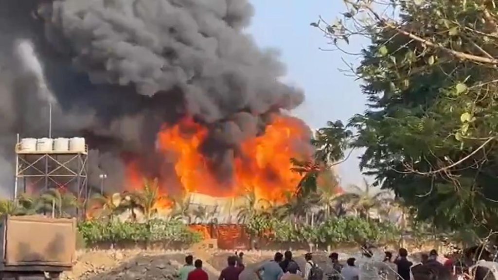 Изображение места пожара в парке развлечений в Раджкоте, Индия, где спасатели работают на фоне разрушений.